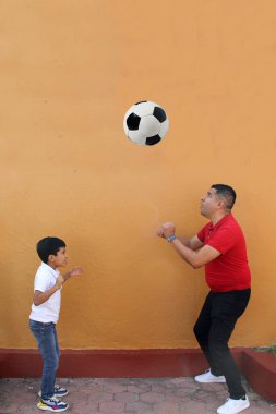 Latin baba ve oğlu futbolu seviyorlar. Futbol maçını izlemek için elleri heyecanlı bir top alıyorlar.