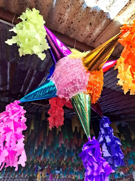Mexican party piata made with a clay or cardboard pot covered in colored paper, with seven spikes, containing fruits and sweets, hung on a string to be broken with a stick on birthdays or Christmas