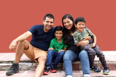 Latin, Hispanic family of mom, dad and children are sitting in the park they look happy enjoying quality time together in harmony
