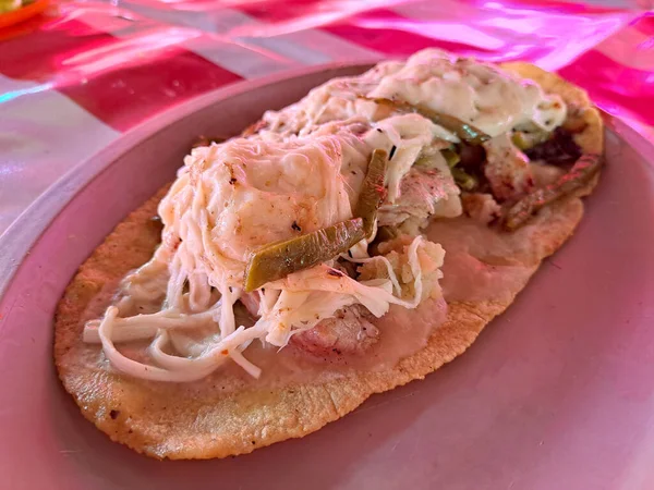 The huarache is a typical Mexican dish, whose shape simulates traditional Mexican sandals. It is made with corn dough, steak, or egg accompanied with sauce, cheese, and beans