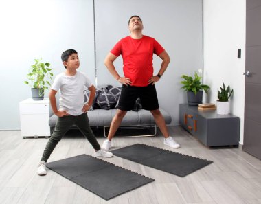 Overweight Latino dad and son exercise at home to lose weight and be healthy to avoid diseases such as diabetes or hypertension