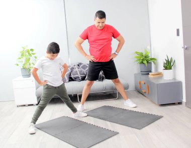 Overweight Latino dad and son exercise at home to lose weight and be healthy to avoid diseases such as diabetes or hypertension