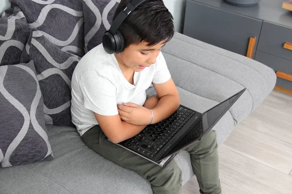 9-year-old Hispanic boy plays video games on his laptop with headphones leading to being overweight and poor sitting posture