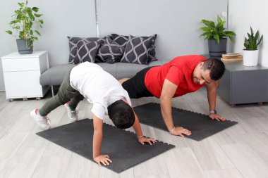 Overweight Latino dad and son exercise at home to lose weight and be healthy to avoid diseases such as diabetes or hypertension