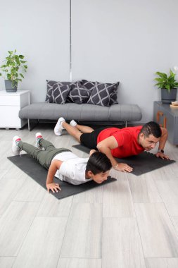 Overweight Latino dad and son exercise at home to lose weight and be healthy to avoid diseases such as diabetes or hypertension