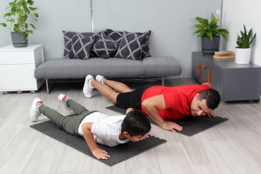 Overweight Latino dad and son exercise at home to lose weight and be healthy to avoid diseases such as diabetes or hypertension