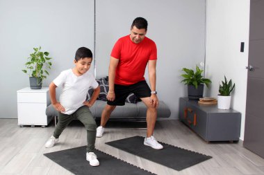 Overweight Latino dad and son exercise at home to lose weight and be healthy to avoid diseases such as diabetes or hypertension