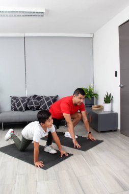 Overweight Latino dad and son exercise at home to lose weight and be healthy to avoid diseases such as diabetes or hypertension