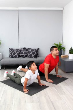 Overweight Latino dad and son exercise at home to lose weight and be healthy to avoid diseases such as diabetes or hypertension