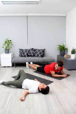 Overweight Latino dad and son exercise at home to lose weight and be healthy to avoid diseases such as diabetes or hypertension