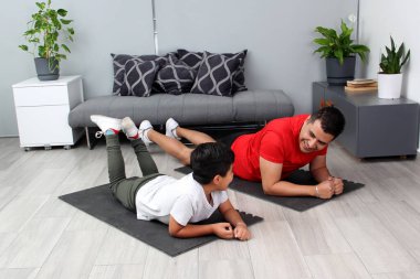 Overweight Latino dad and son exercise at home to lose weight and be healthy to avoid diseases such as diabetes or hypertension