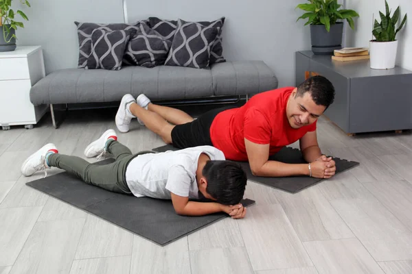 Overweight Latino dad and son exercise at home to lose weight and be healthy to avoid diseases such as diabetes or hypertension
