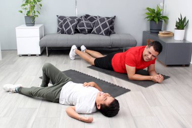 Overweight Latino dad and son exercise at home to lose weight and be healthy to avoid diseases such as diabetes or hypertension