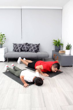 Overweight Latino dad and son exercise at home to lose weight and be healthy to avoid diseases such as diabetes or hypertension