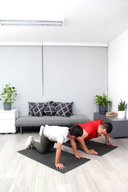 Overweight Latino dad and son exercise at home to lose weight and be healthy to avoid diseases such as diabetes or hypertension