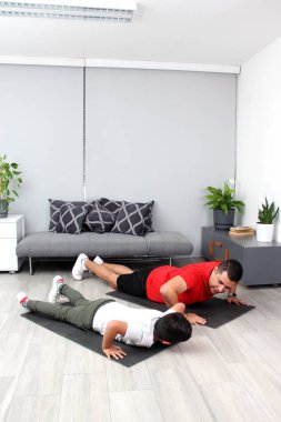 Overweight Latino dad and son exercise at home to lose weight and be healthy to avoid diseases such as diabetes or hypertension