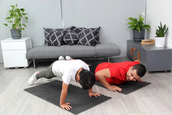 Overweight Latino dad and son exercise at home to lose weight and be healthy to avoid diseases such as diabetes or hypertension