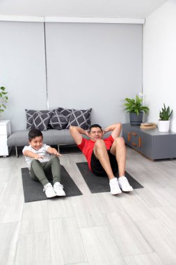 Overweight Latino dad and son exercise at home to lose weight and be healthy to avoid diseases such as diabetes or hypertension
