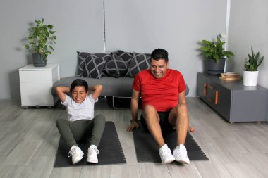 Overweight Latino dad and son exercise at home to lose weight and be healthy to avoid diseases such as diabetes or hypertension