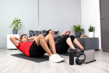 Latino adult couple of man and woman exercise at home taking online class they see the laptop in their living room together they exercise to avoid diabetes and hypertension