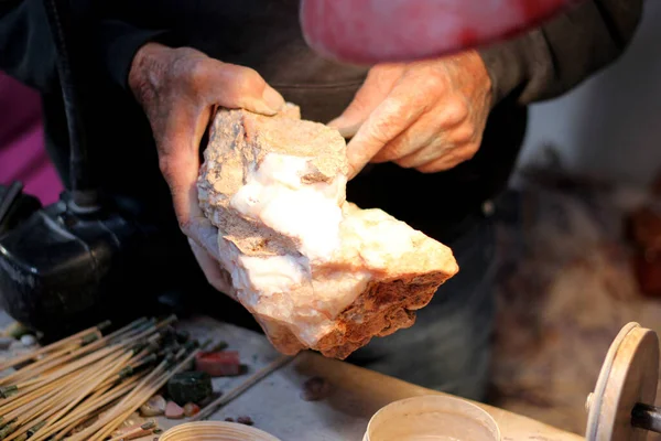 貴重な宝石を形成するためにオパール石や鉱物を研磨ワークショップで働く高齢職人の手 — ストック写真