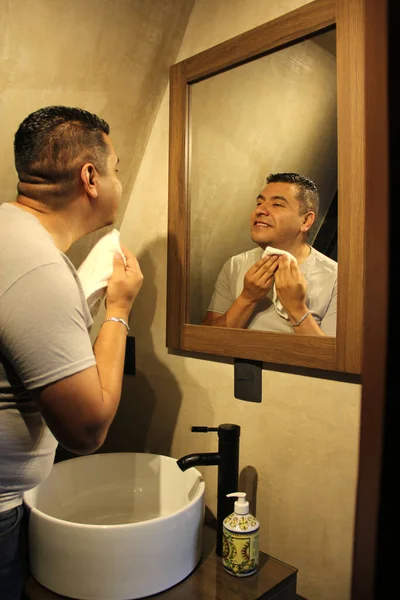 40歳の暗い肌のラテン系の大人の男は 彼がワックスを恐れているので 自宅でバスルームミラーの前にカミソリで剃刀で剃る — ストック写真
