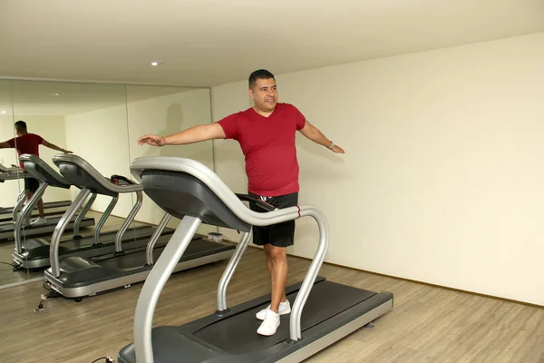 stock image Overweight dark-haired latino adult man exercises on treadmill in gym to relax and avoid diabetes and hypertension