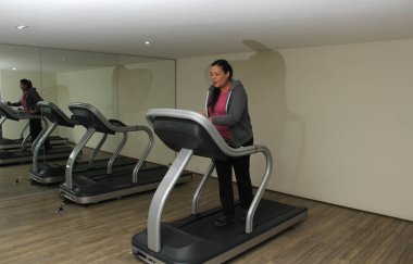 Latin yetişkin kadın diyabet ve hipertansiyondan kaçınmak için spor salonunda koşu bandında egzersiz yapıyor.