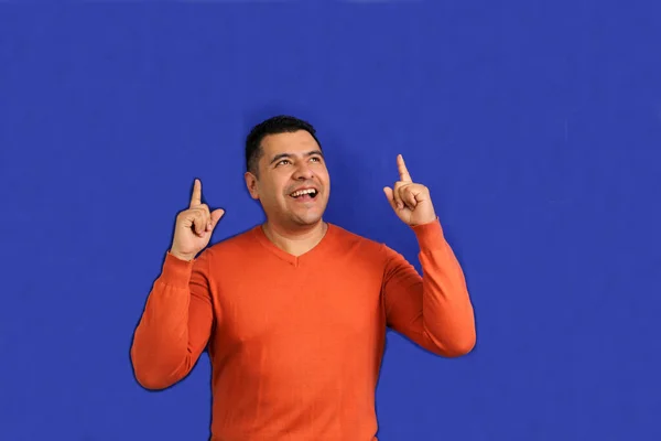 大人男40歳Latinoブルネットとともにオレンジセーターポイントとともに彼の手青背景色コピースペースとともに幸せと自然な表現 — ストック写真