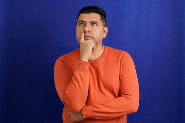 Yetişkin, koyu tenli, 40 'lı yaşlarda Latin bir adam düşünceli ve düşünceli görünüyor.