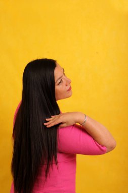 Latin yetişkin kadın uzun düz saçlarını gösteriyor. Sağlıklı, parlak ve ipeksi.