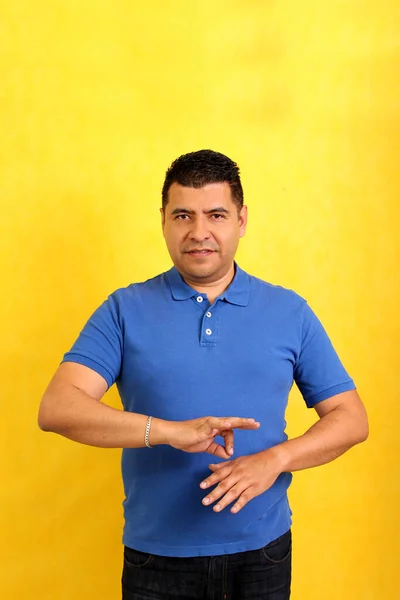 Dark-haired Latino adult man uses sign language typical of deaf people to establish a channel of communication with his social environment