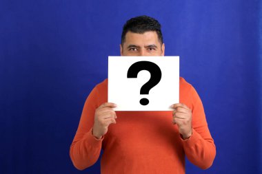 Latin esmer yetişkin bir adam bir soru işareti gösterir. Mucizeler, şüpheler, şüpheliler, varsayımlar, korkular ve güvensizlikler.