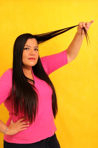 Latin adult woman with very long straight hair suffers and is sad because her hair is a mess and is very damaged with split ends