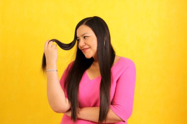 Uzun düz saçlı Latin yetişkin bir kadın sağlıklı, parlak ve ipeksi saçlara sahip olduğu için mutlu.