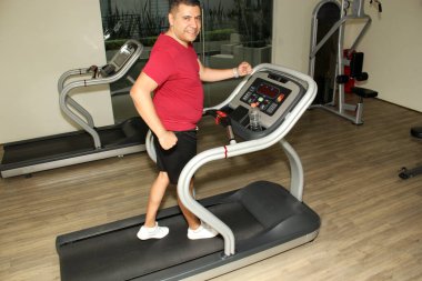 Kırk yaşındaki koyu renk saçlı Latin yetişkin adam, tendonit, tendon yırtılması ya da çapraz bağ zedelenmesi gibi hastalıklar için koşu banisinde bacaklarını çalıştırıyor.