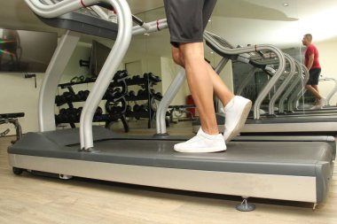 Kırk yaşındaki koyu renk saçlı Latin yetişkin adam, tendonit, tendon yırtılması ya da çapraz bağ zedelenmesi gibi hastalıklar için koşu banisinde bacaklarını çalıştırıyor.