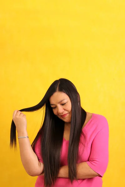 40岁的拉丁裔成年女性通过治疗和护理 用手指展示了她那长长的 健康的 闪亮的 柔滑的头发 — 图库照片