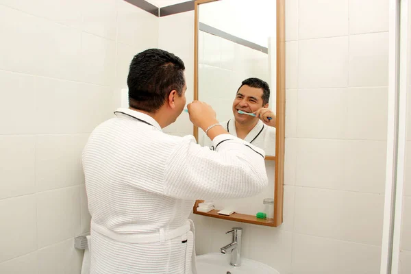 40歳の暗い肌のラテン人が鏡を見て 彼の口腔の健康の世話をするバスルームで彼の歯を磨く — ストック写真