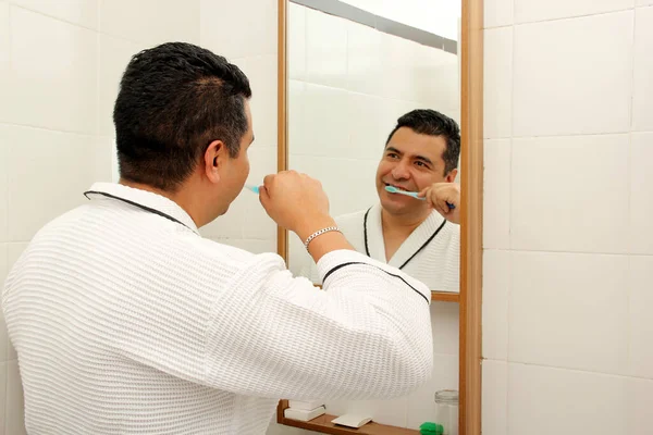 40歳の暗い肌のラテン人が鏡を見て 彼の口腔の健康の世話をするバスルームで彼の歯を磨く — ストック写真