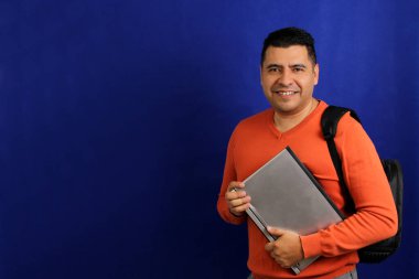 Koyu renk saçlı 40 yaşındaki Latin adam işe dizüstü bilgisayarıyla sırt çantasını getiriyor ya da coşkuyla çalışıyor.