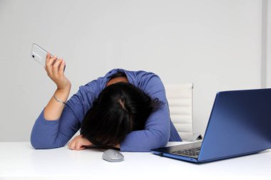 Kırk yaşında Latin bir kadın, bilgisayarında çalıştığı iş stresinden dolayı bitkin, zihinsel, fiziksel ve duygusal yorgunluğa yol açan laptopuyla çalışıyor.