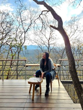 40 yaşında boşanmış, bekar, yetişkin bir Latin kadın, ormanın ortasında kulübesinde oturmuş bir bardak kırmızı şarap içiyor. Rahatlama, sükunet ve sakinlik.