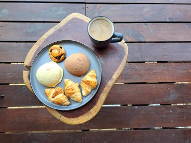 Ormandaki bir kulübenin terasında kahvaltı. Tahta bir masanın üzerinde. Kahve ve tatlı ekmek güne başlamaya hazır.