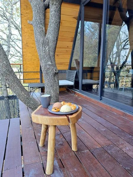 Breakfast on the terrace of a cabin in the woods on a wooden table with coffee and sweet bread ready to start the day