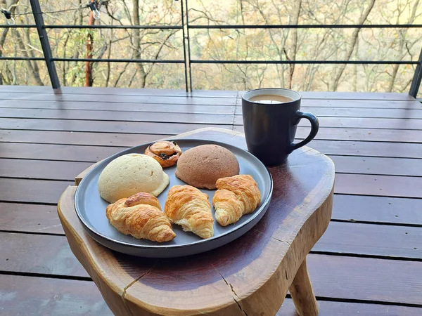 Breakfast on the terrace of a cabin in the woods on a wooden table with coffee and sweet bread ready to start the day