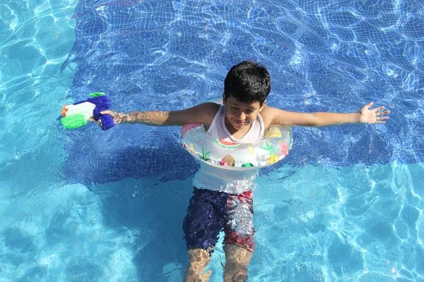 9歳の茶色の髪のラテン系の男の子がプールで泳ぎ 日焼け止めで太陽の下で休暇を楽しんでいます — ストック写真