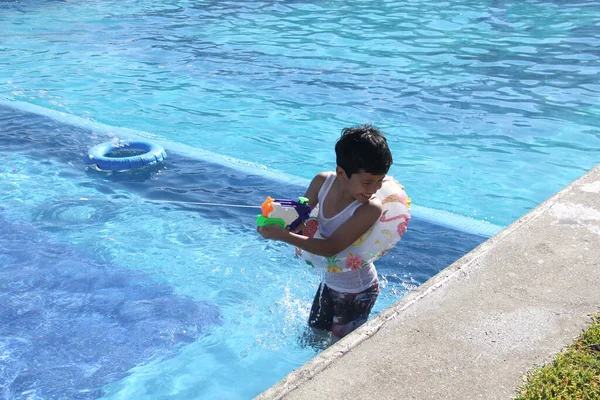 9歳の茶色の髪のラテン系の男の子がプールで泳ぎ 日焼け止めで太陽の下で休暇を楽しんでいます — ストック写真