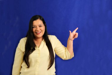 40 yaşındaki Latin kadın, sevdiği bir şeyi parmaklarıyla işaret ediyor. Ürünler ve promosyonlar gibi sürprizler ve heyecanlar.