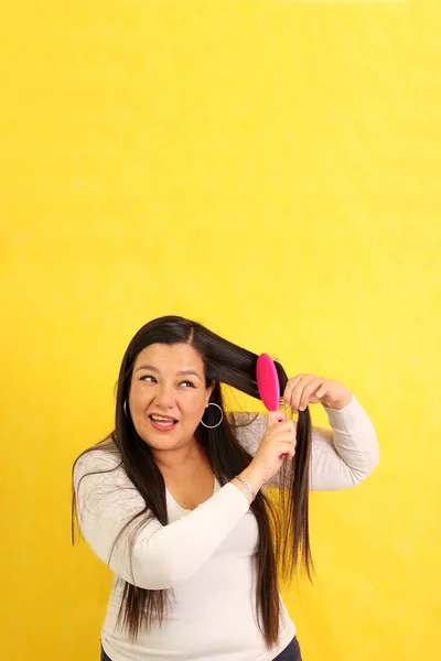 40岁的拉丁裔成年妇女很难梳头 因为她的头发因干燥而结结缠结在一起 — 图库照片